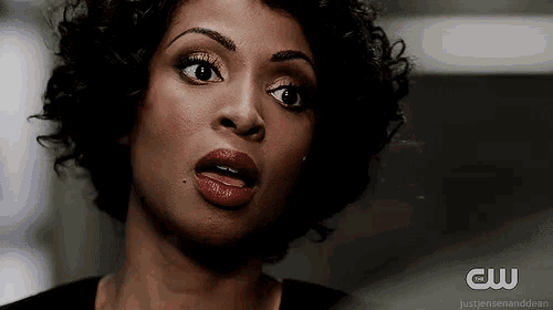 a woman with curly hair is making a funny face with her mouth open .