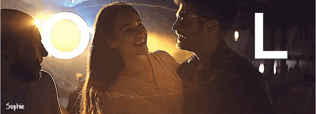 a man and a woman are dancing in a dark room with the letter l behind them