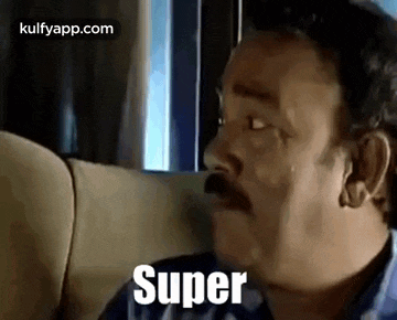 a man with a mustache is sitting on a couch with his eyes closed and the word super written on his face .