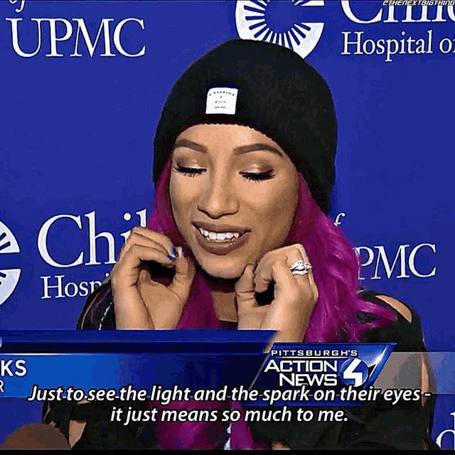 a woman with pink hair and a black beanie is talking on a tv screen that says action news 4