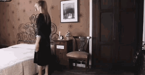 a woman in a black dress is standing in front of a bed with a sign on the nightstand that says reception