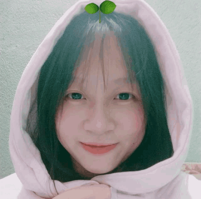 a young girl wearing a pink hoodie with a plant on her head