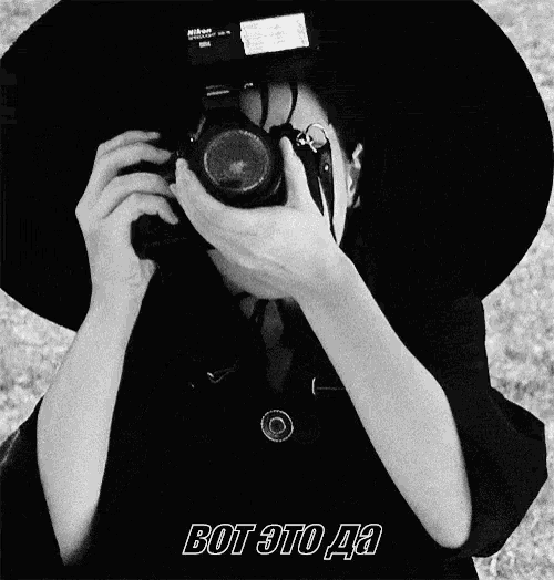 a black and white photo of a person taking a picture with a nikon camera ..