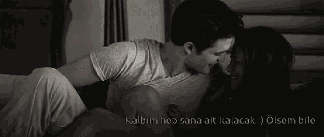 a black and white photo of a man kissing a woman with the words kalbim hep sana ait kalacak on the bottom