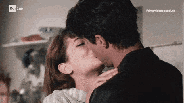 a man and woman kissing in front of a sign that says prima visione absolute