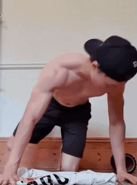 a shirtless man is doing push ups with a hat that has the letter s on it