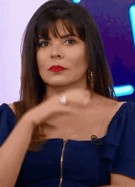 a woman wearing a blue off the shoulder top has red lipstick on her lips
