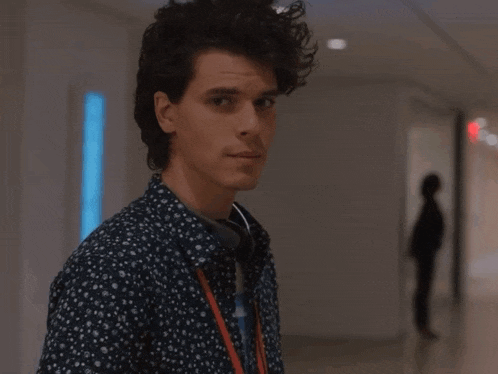 a man walking down a hallway with a lanyard around his neck