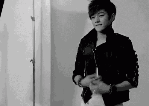 a young man in a leather jacket is standing in a room .