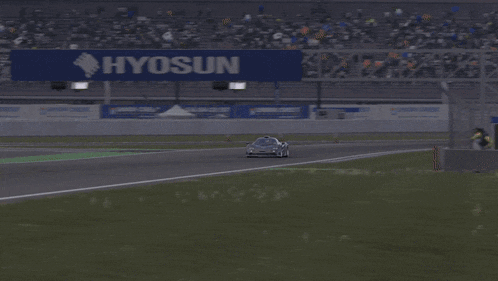 a car is driving down a race track with a sign in the background that says toyota