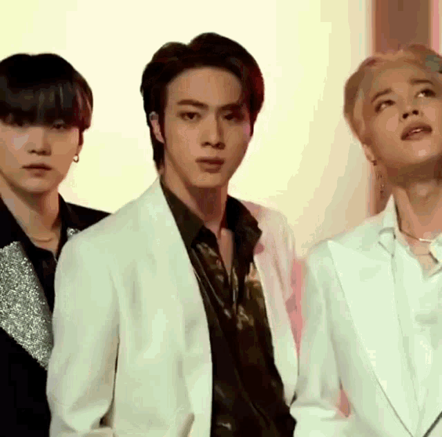 a group of young men are standing next to each other and one of them is wearing a white jacket .