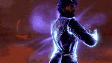 a man with a beard is standing in a dark room with purple lights behind him