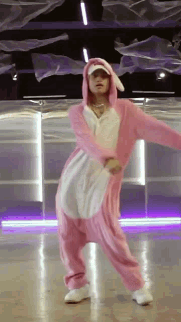 a person in a pink and white bunny costume is dancing in a dance studio .