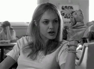 a black and white photo of a woman holding a stuffed animal in her hand .