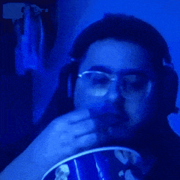 a man wearing glasses and headphones is eating food from a bowl in a dark room .