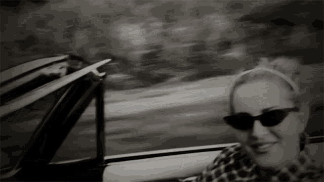 a woman wearing sunglasses and a headband is driving a car