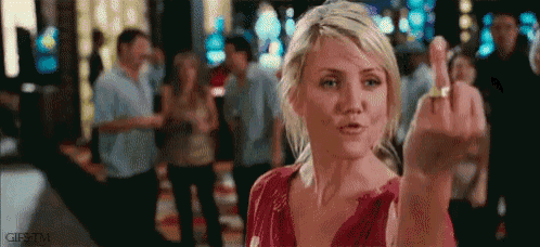 a woman in a red shirt is giving the middle finger to the camera .