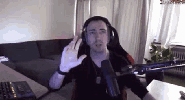a man wearing headphones is sitting in front of a microphone in a room .