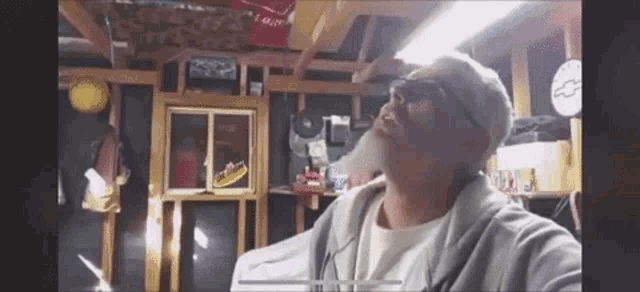a man with a beard is standing in a garage with a sign that says schweppes