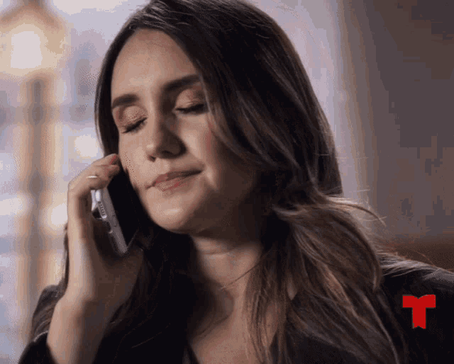 a woman talking on a cell phone with a red t on the bottom