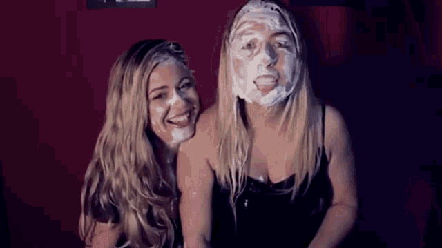 two women are sitting next to each other with their faces covered in shaving cream .