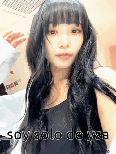 a woman with long black hair is wearing a black tank top with the words soy solo de ysa written below her