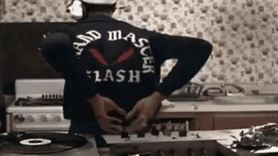 a man wearing a black jacket with the word flash on the back is standing in a kitchen .
