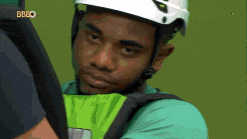 a man wearing a white helmet and a green shirt with the letters bbbo on the bottom right