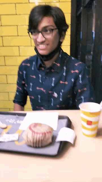 a man wearing a mask sits at a table with a mcdonald 's cup