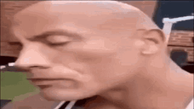 a close up of a bald man with his eyes closed .