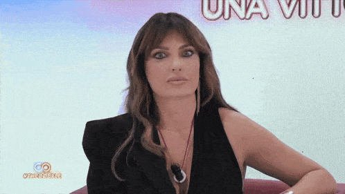 a woman sitting in front of a screen that says una viu
