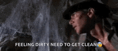 a man in a hat is standing in front of a wall with the words feeling dirty need to get clean written on it .