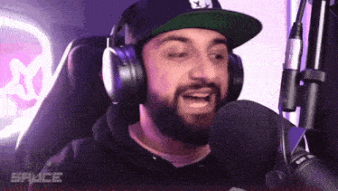 a man wearing headphones and a hat is talking into a microphone with the word sauce in the corner