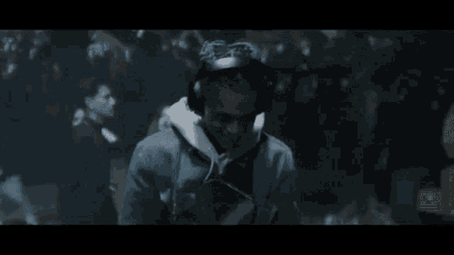 a man wearing headphones is standing in a crowd of people in a dark room .