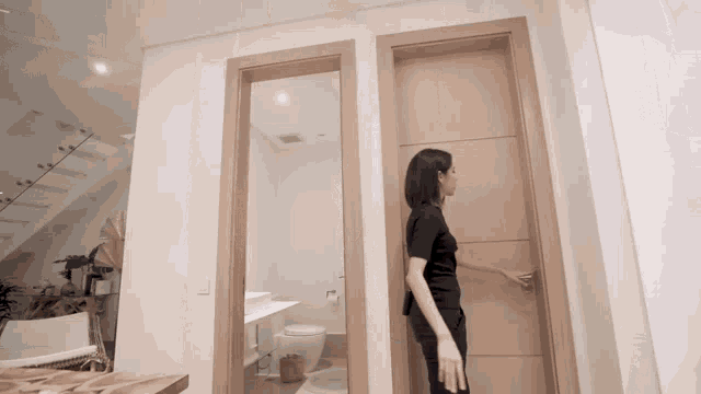 a woman opens a door to a bathroom with a toilet