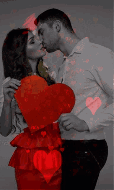 a man and a woman kissing while holding a red heart that says vca on it