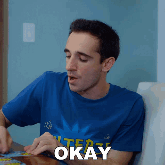 a man wearing a blue shirt that says " okay " on it