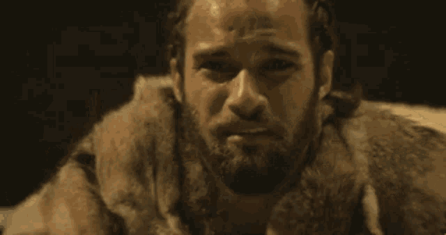 a man with a beard is crying while sitting in front of a candle .