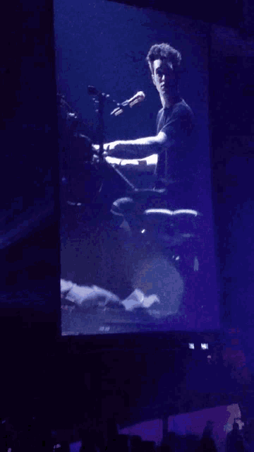 a screen shows a person playing a piano with purple lights behind them