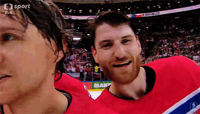 two hockey players are smiling in front of a crowd and the word sport is on the bottom left