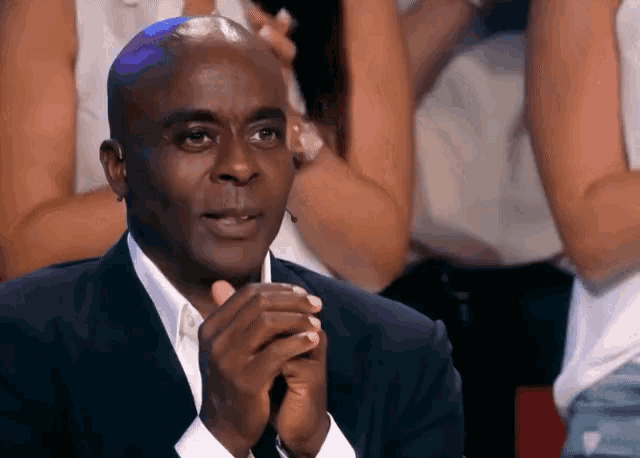 a man in a suit is clapping his hands together