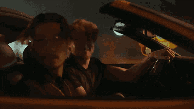 a man driving a car with another man in the back seat
