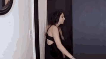 a woman in a black dress is standing in front of a door .