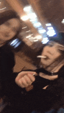 a blurry photo of a woman smoking a cigarette and a man holding a lighter