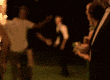 a man and a woman are dancing in a field at night .
