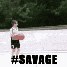 a young boy is holding a basketball and the words #savage are behind him