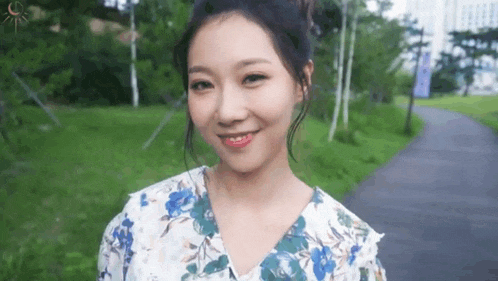 a woman in a floral dress is smiling and looking at the camera .