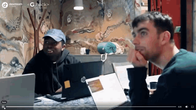 two men are sitting at a table with laptops in front of them and the words devoteam on the bottom
