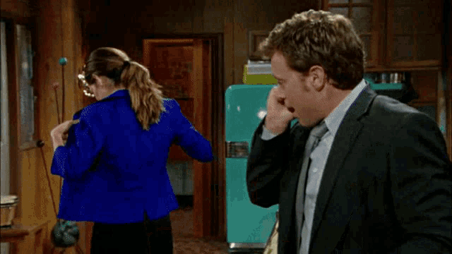 a man in a suit stands next to a woman in a bra