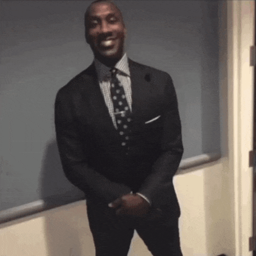 a man in a suit and tie smiles while standing in front of a window